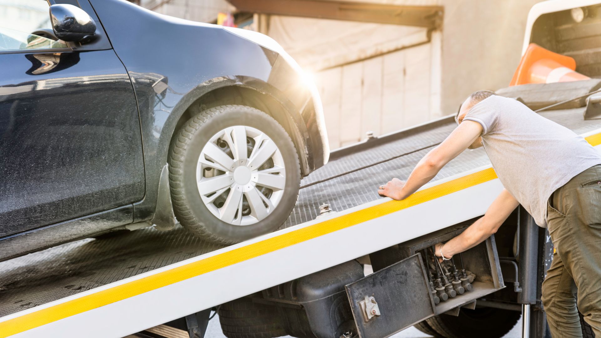 Car being loaded onto a tow truck's flatbed with yellow safety markings