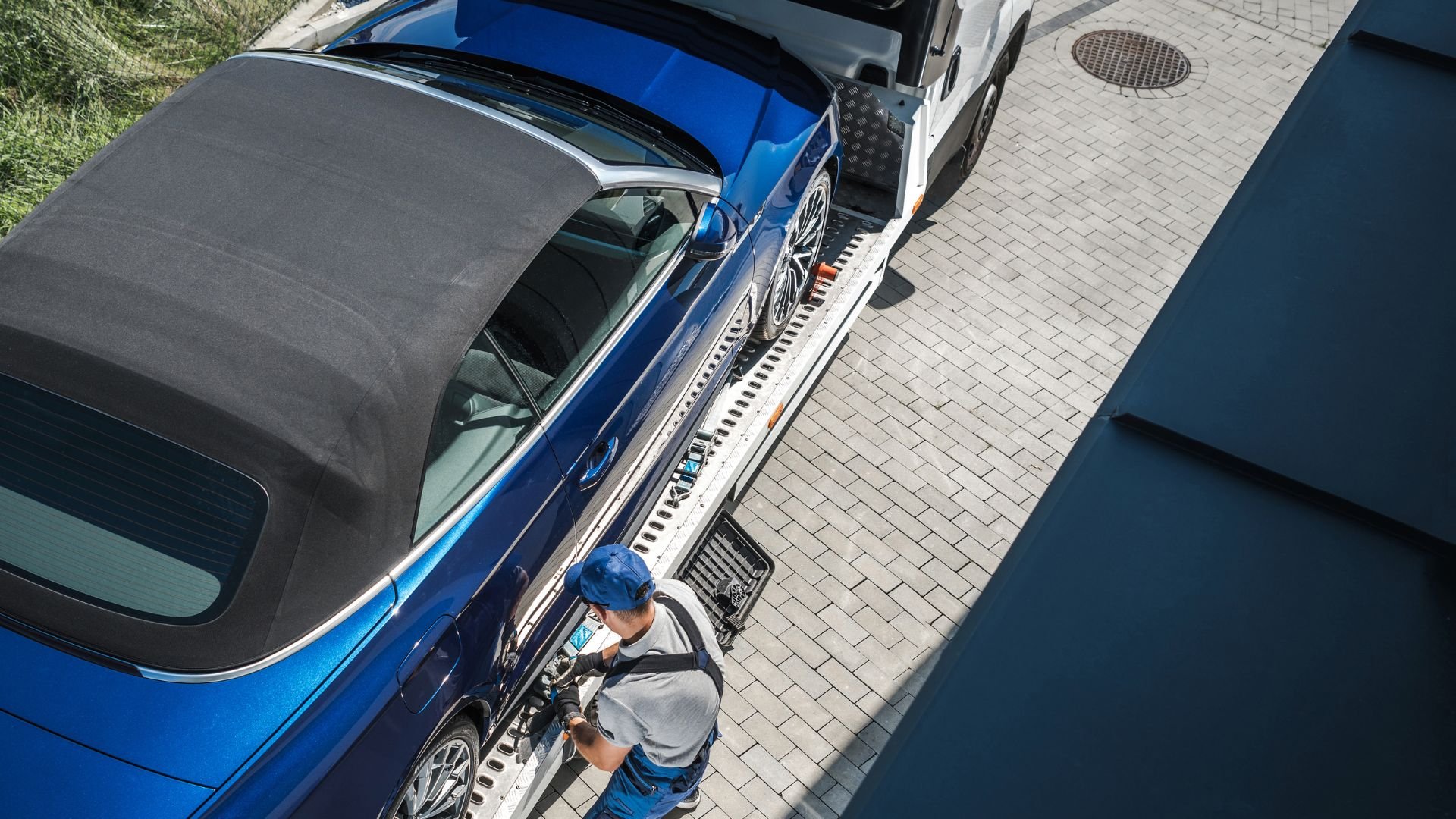 Blue car being loaded onto a vehicle transport trailer