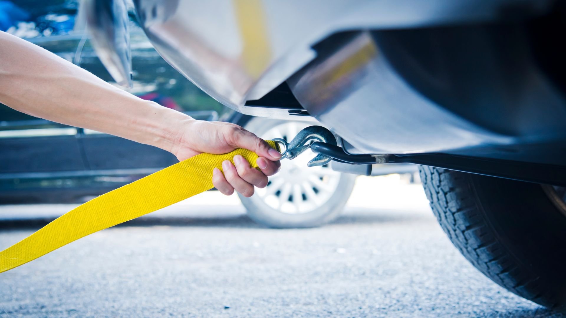 Yellow tow strap hooking to car for vehicle recovery or towing